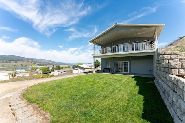 rear view of property with a lawn, a mountain view, and a balcony