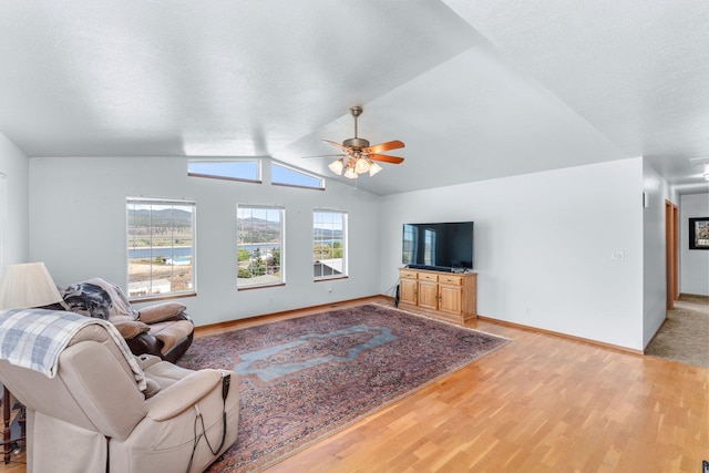 living area featuring baseboards, ceiling fan, light wood finished floors, and lofted ceiling