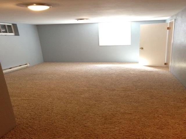unfurnished room featuring a baseboard radiator and carpet