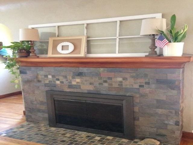 interior details with a tiled fireplace, baseboards, and wood finished floors