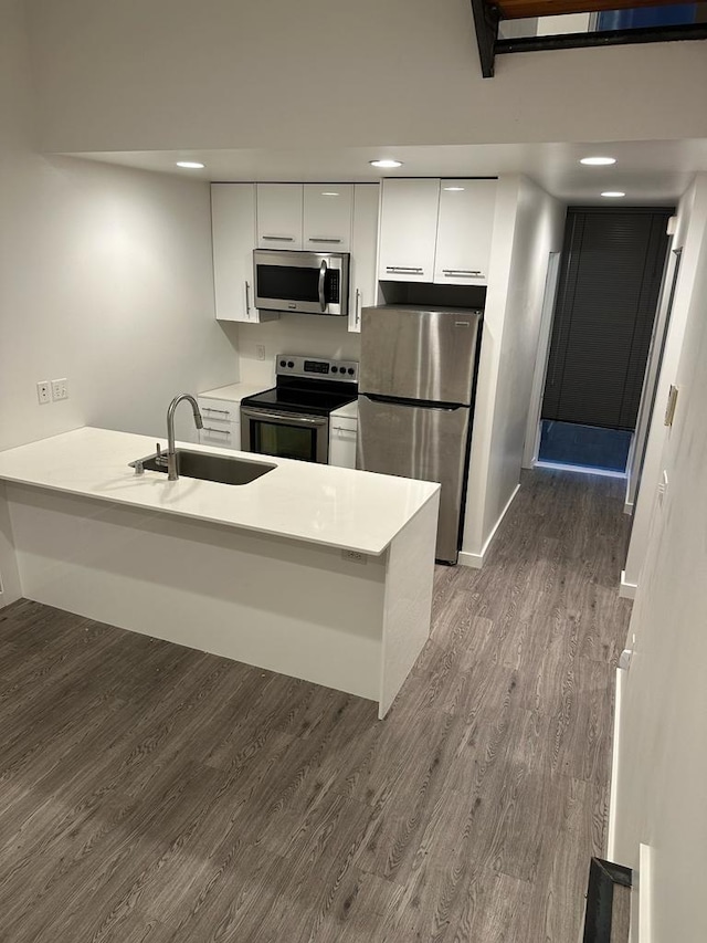 kitchen featuring white cabinets, stainless steel appliances, dark wood-style floors, and a sink