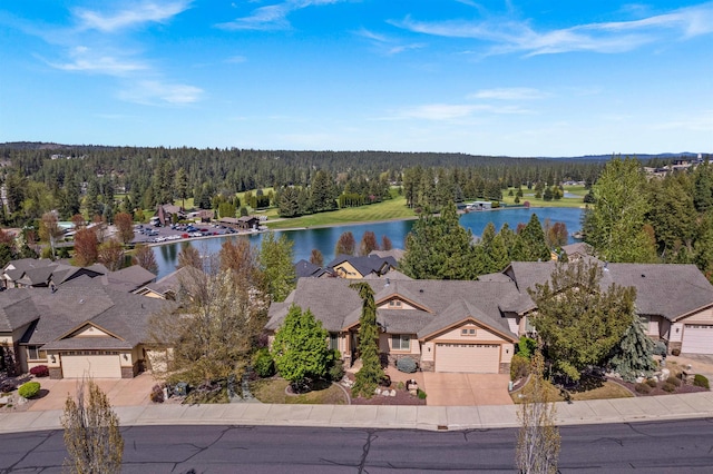 drone / aerial view featuring a residential view, a water view, and a forest view