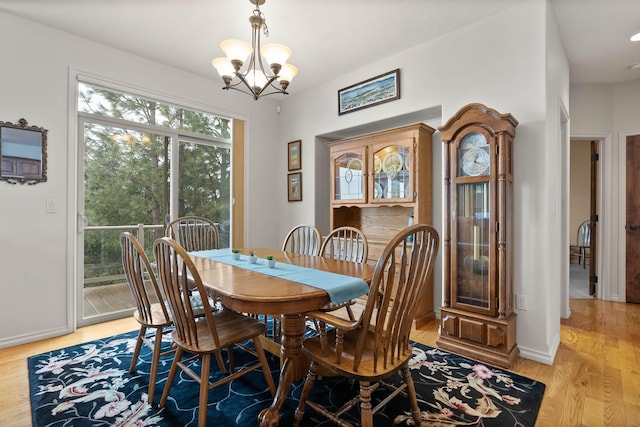 dining room featuring baseboards, a chandelier, and light wood-style floors