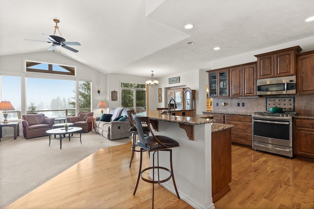 kitchen with dark stone countertops, glass insert cabinets, a breakfast bar, stainless steel appliances, and recessed lighting
