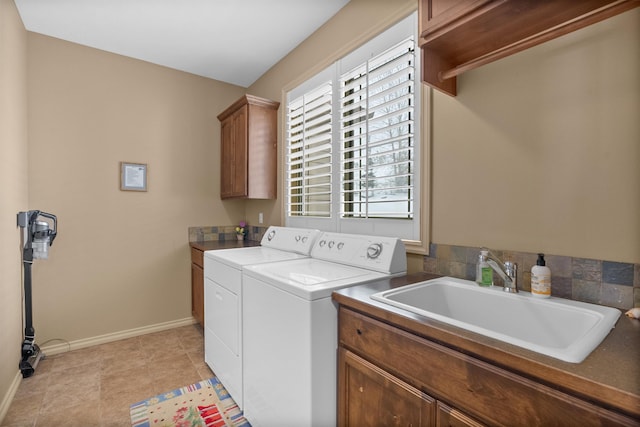clothes washing area with a sink, baseboards, cabinet space, and washer and clothes dryer