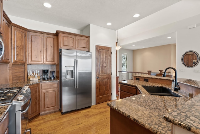 813 E Wandermere Estates Ln, Spokane, WA 99208 - kitchen featuring appliances with stainless steel finishes, light wood-style flooring, dark stone counters, recessed lighting, and brown cabinets