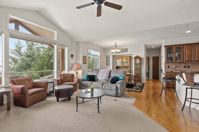 living area featuring vaulted ceiling, recessed lighting, ceiling fan with notable chandelier, and light wood-type flooring