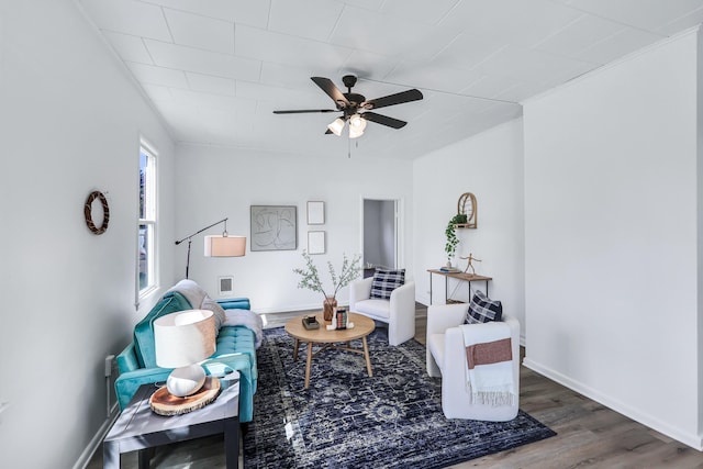 living area with baseboards, ceiling fan, and wood finished floors