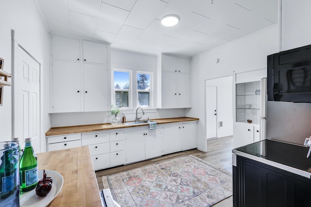 kitchen featuring white cabinets, wood counters, black microwave, and a sink