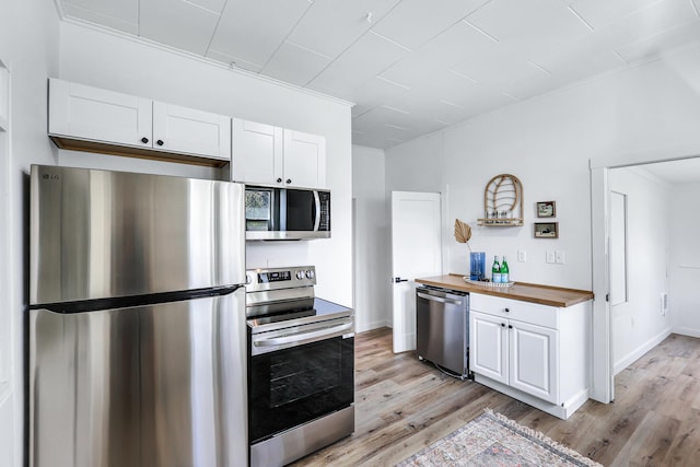 kitchen with light wood-style floors, stainless steel appliances, butcher block counters, and white cabinetry