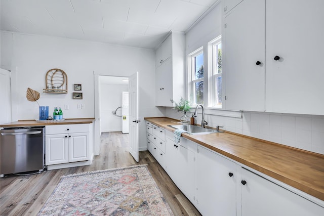 kitchen featuring light wood-style flooring, dishwasher, a sink, wood counters, and white cabinetry