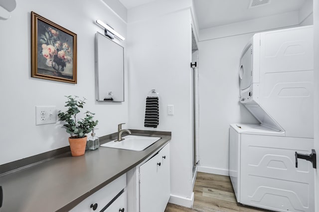 bathroom featuring vanity, wood finished floors, baseboards, stacked washing maching and dryer, and a stall shower