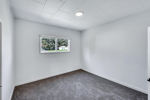 unfurnished room with baseboards and dark carpet