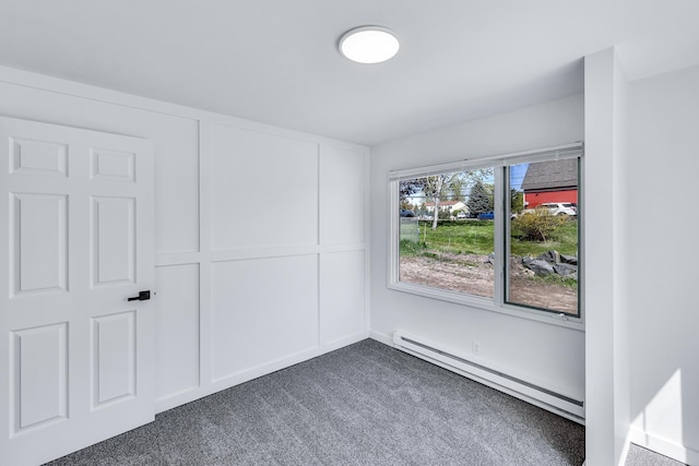 spare room with dark colored carpet and baseboard heating