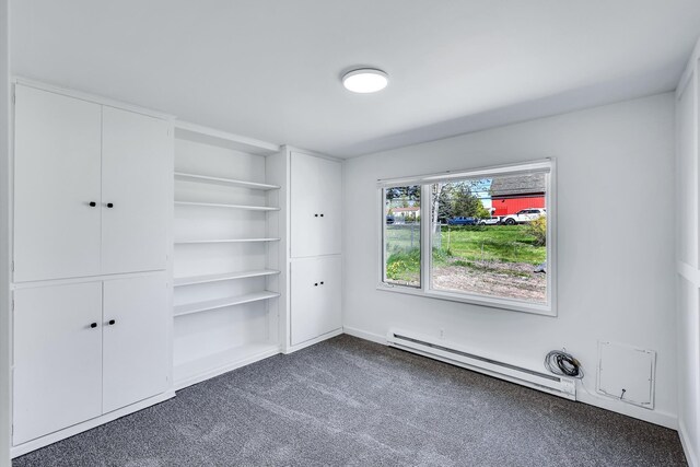 unfurnished bedroom with a baseboard heating unit and dark carpet