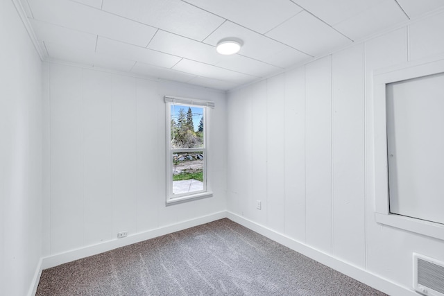carpeted spare room with baseboards, a decorative wall, and visible vents