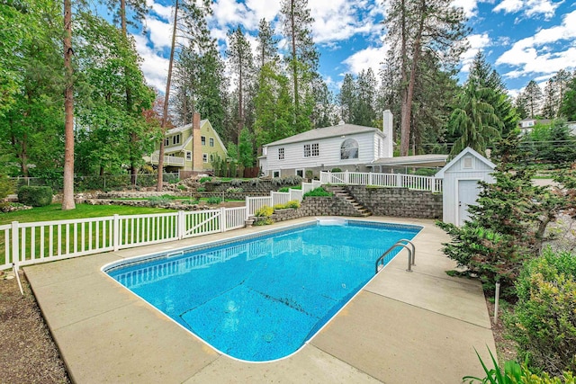 view of swimming pool featuring fence, a shed, a fenced in pool, stairs, and an outbuilding