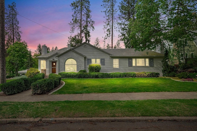 ranch-style home with a chimney and a front lawn