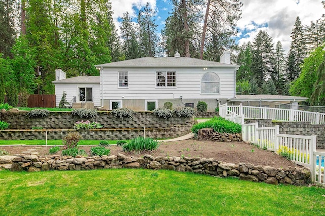 rear view of house featuring a lawn, fence, and a chimney