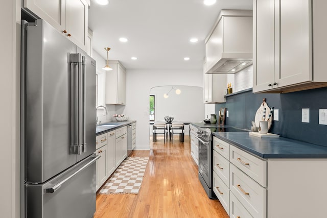 kitchen featuring dark countertops, appliances with stainless steel finishes, custom exhaust hood, and a sink