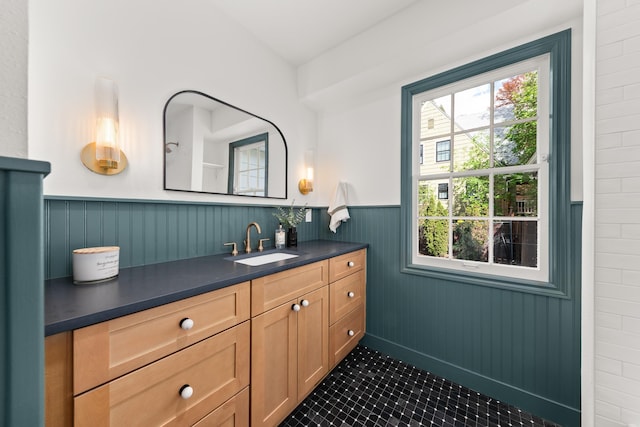 bathroom with a healthy amount of sunlight, vanity, tile patterned flooring, and wainscoting