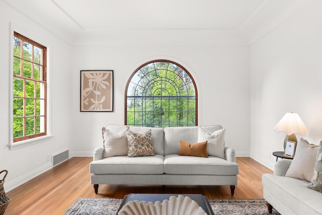 living area featuring visible vents, light wood-style floors, and a healthy amount of sunlight