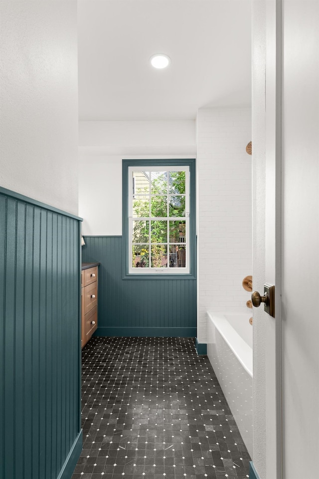 bathroom featuring vanity, washtub / shower combination, and wainscoting