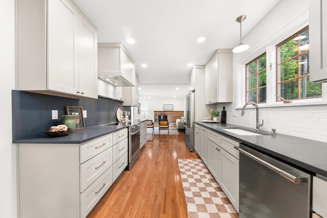 kitchen featuring backsplash, appliances with stainless steel finishes, dark countertops, a sink, and white cabinetry