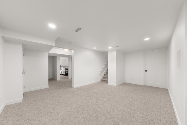 finished below grade area featuring recessed lighting, baseboards, stairway, and light colored carpet