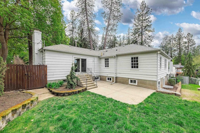 rear view of house with a lawn, a patio, fence, and a chimney