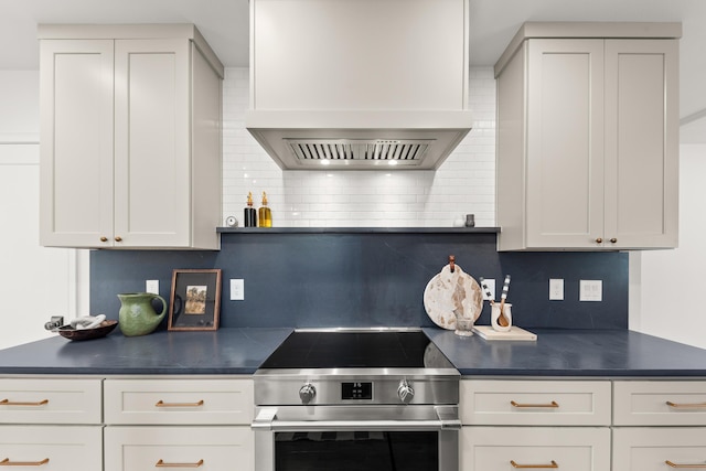 kitchen featuring custom range hood, stainless steel range with electric stovetop, dark countertops, and tasteful backsplash