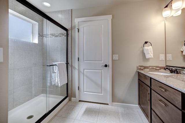 bathroom with vanity, tile patterned flooring, baseboards, and a shower stall