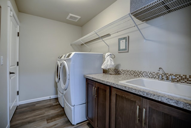 laundry room with dark wood-style flooring, washing machine and dryer, baseboards, a sink, and cabinet space