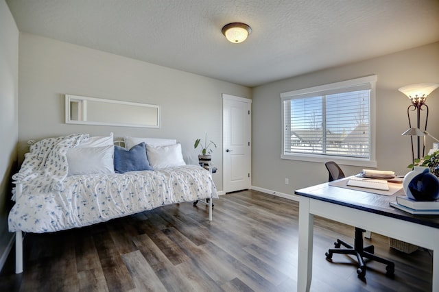 bedroom with baseboards, a textured ceiling, and wood finished floors