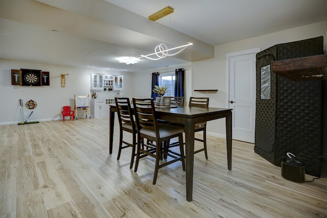 dining room featuring baseboards, light wood-style flooring, and a notable chandelier