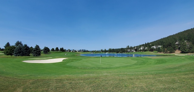 view of home's community featuring a lawn, view of golf course, and a water view
