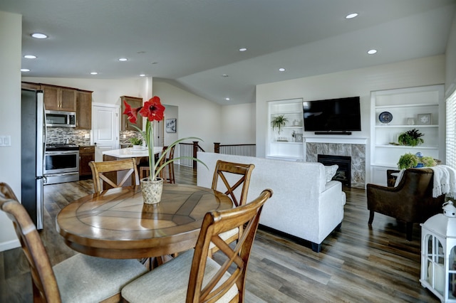 dining room with recessed lighting, wood finished floors, lofted ceiling, and a fireplace