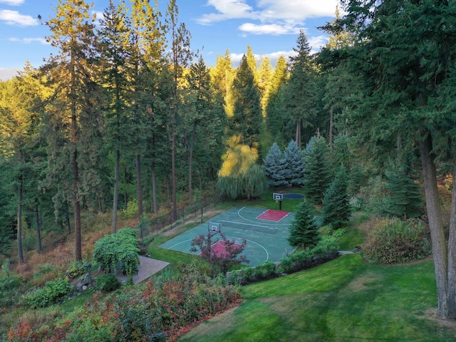 view of basketball court featuring a yard, a view of trees, and community basketball court