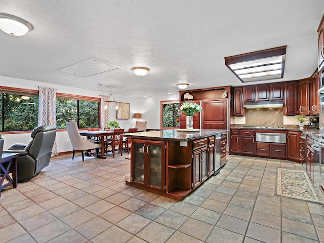 kitchen with a warming drawer, plenty of natural light, decorative backsplash, and under cabinet range hood