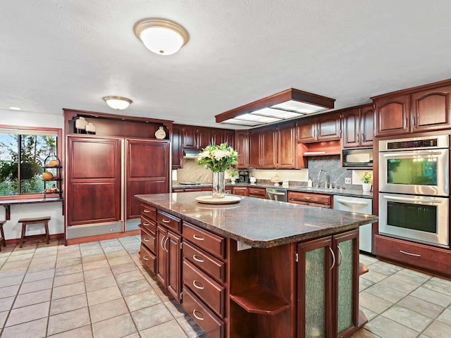 kitchen with open shelves, appliances with stainless steel finishes, dark stone countertops, tasteful backsplash, and a kitchen island