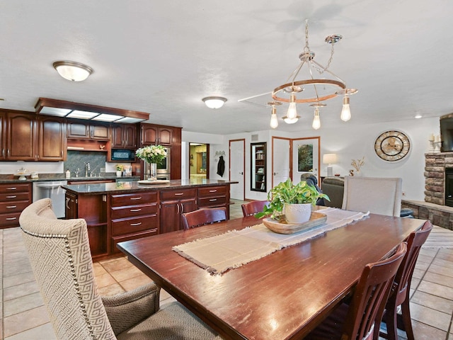 dining area featuring light tile patterned floors, an inviting chandelier, and a fireplace