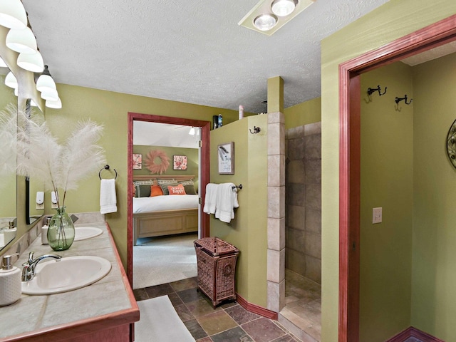 bathroom featuring walk in shower, a sink, ensuite bath, double vanity, and a textured ceiling