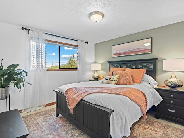 bedroom with a textured ceiling, baseboards, and light carpet