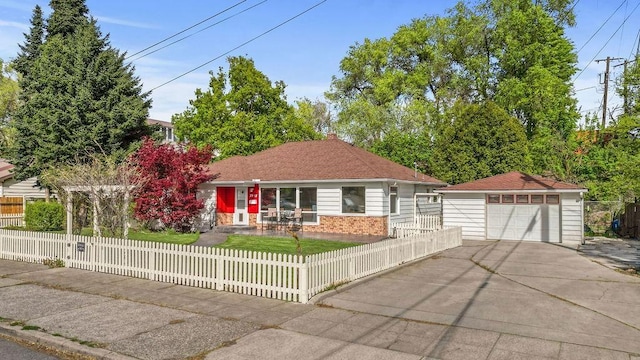 ranch-style home featuring driveway, a fenced front yard, a detached garage, brick siding, and an outdoor structure