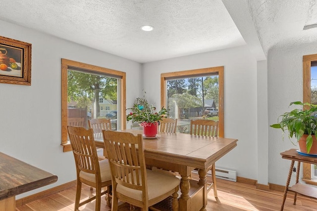 dining space with a healthy amount of sunlight, light wood finished floors, and a textured ceiling