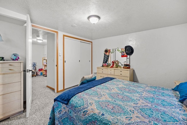 bedroom with a textured ceiling, a textured wall, carpet, and a closet