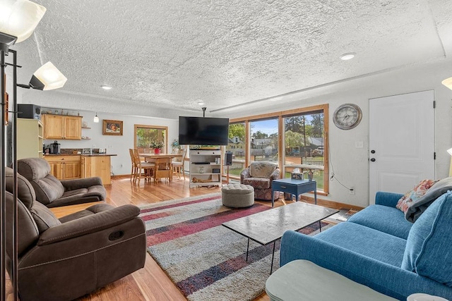 living room featuring a textured ceiling, baseboards, and light wood-type flooring