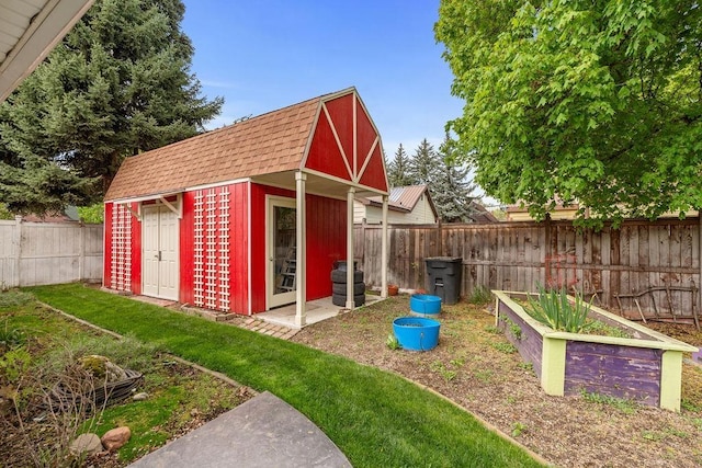 view of outdoor structure featuring a fenced backyard, an outbuilding, and a vegetable garden