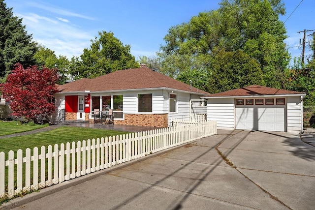 ranch-style house featuring a fenced front yard, brick siding, a garage, an outbuilding, and driveway