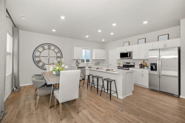 kitchen featuring recessed lighting, appliances with stainless steel finishes, a kitchen island, and light wood-type flooring